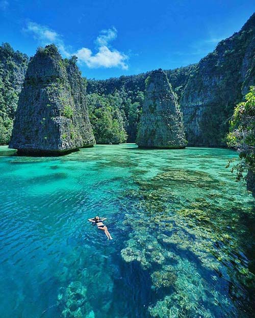 Young lady guest of a private charter swimming in Wayag Island Group