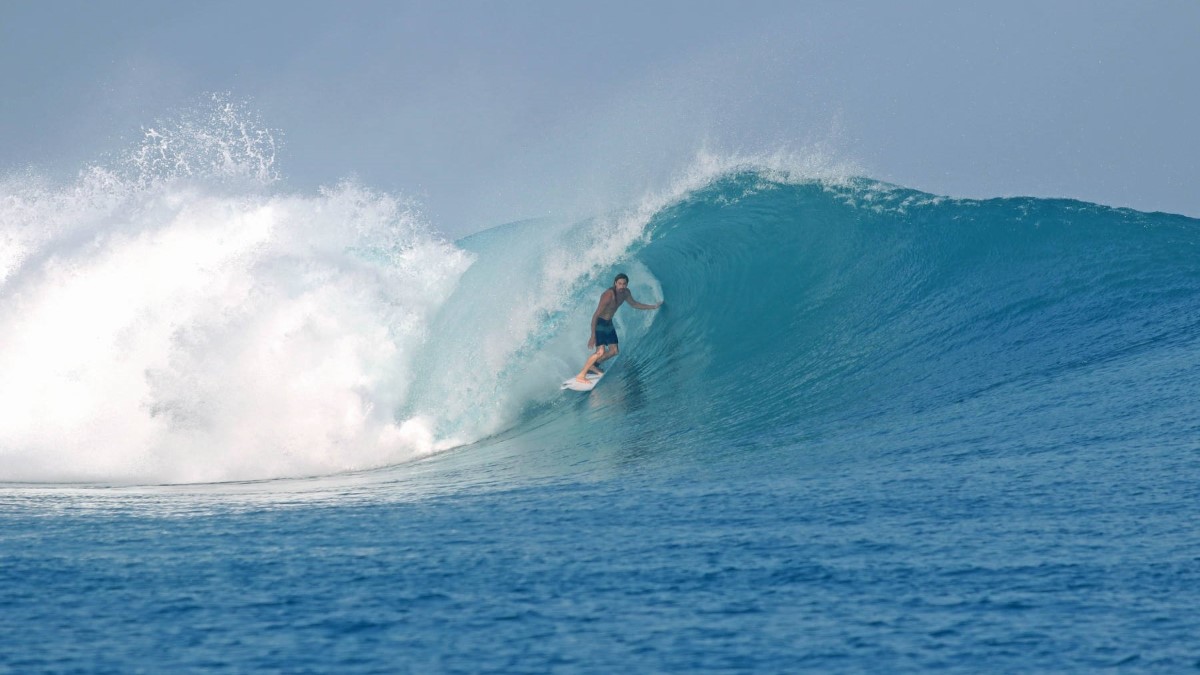 A surfer experiences the incredible Mentawais waves from Awera Resort Surfer on a surf board is surfing an incredible wave in the Mentawai Islands in front Awera Resort