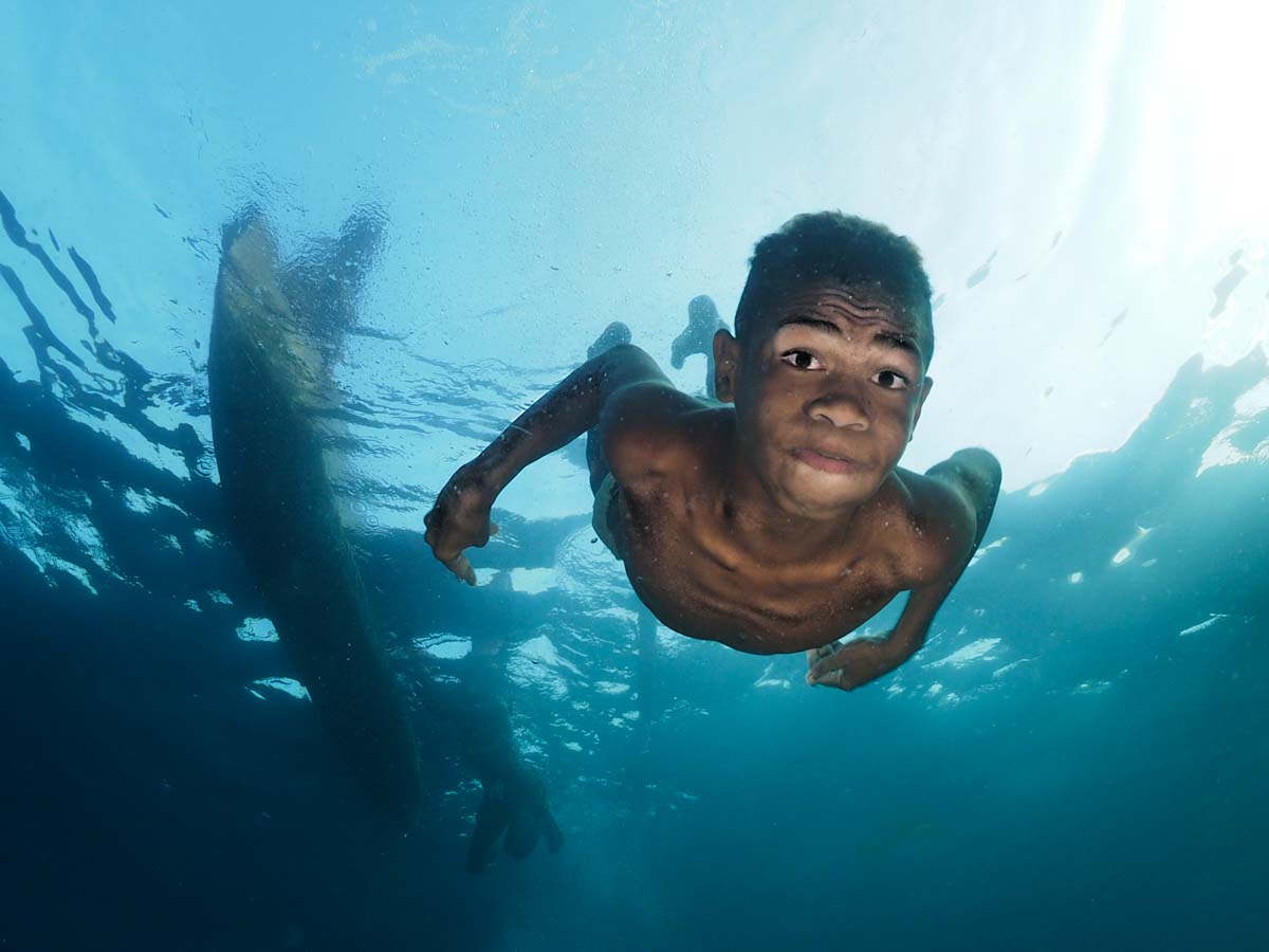 Kid of Alor diving in apnea under his canoe